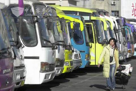 一位回家的旅客經(jīng)過?？吭谄囌纠镎b待發(fā)的大客車前